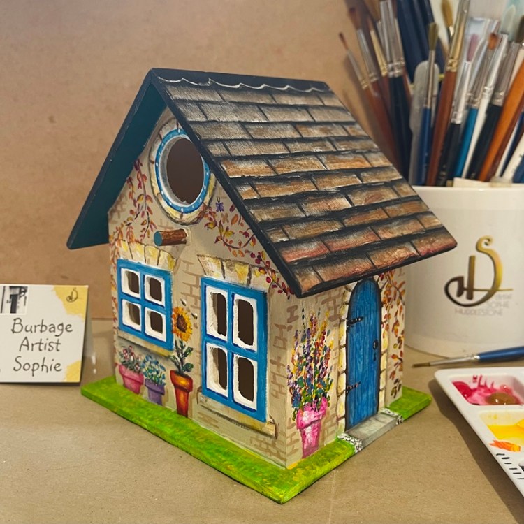 photo showing the hand painted bird house at an angle, at burbage artist sophie art studio