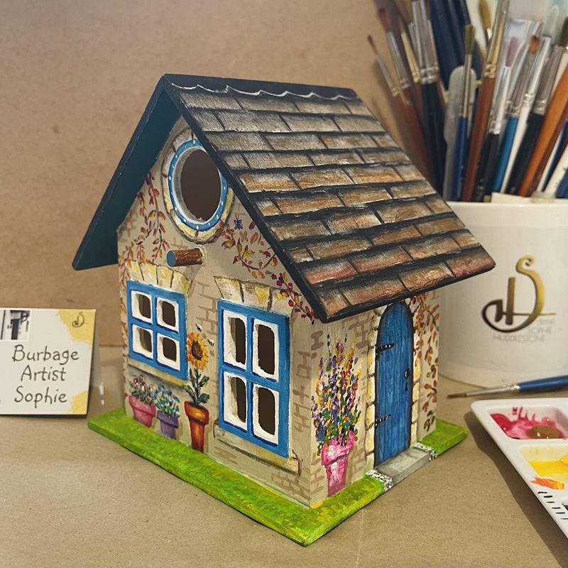 photo showing the hand painted bird house at an angle, at burbage artist sophie art studio