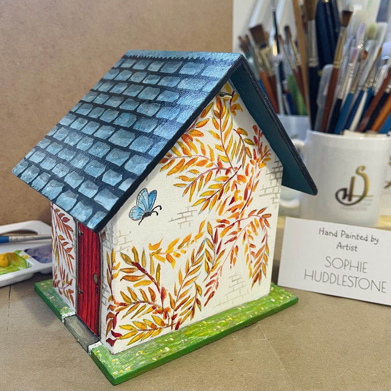 photo showing the hand painted bird house at an angle, at burbage artist sophie art studio