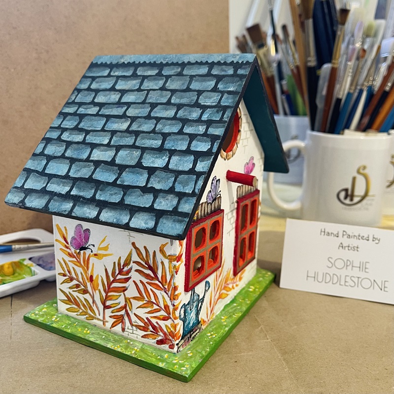 photo showing the hand painted bird house at an angle, at burbage artist sophie art studio