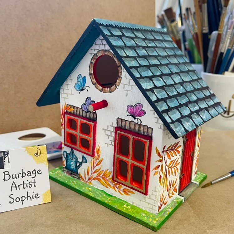 photo showing the hand painted bird house at an angle, at burbage artist sophie art studio