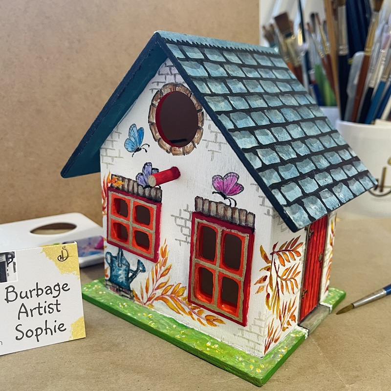 photo showing the hand painted bird house at an angle, at burbage artist sophie art studio