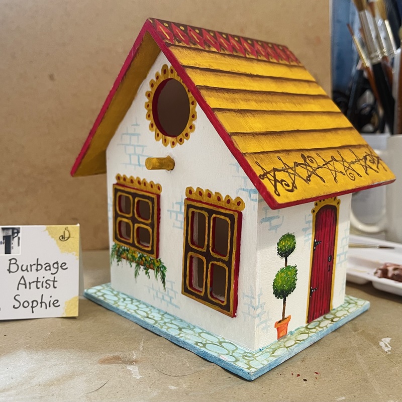 photo showing the hand painted bird house at an angle, at burbage artist sophie art studio